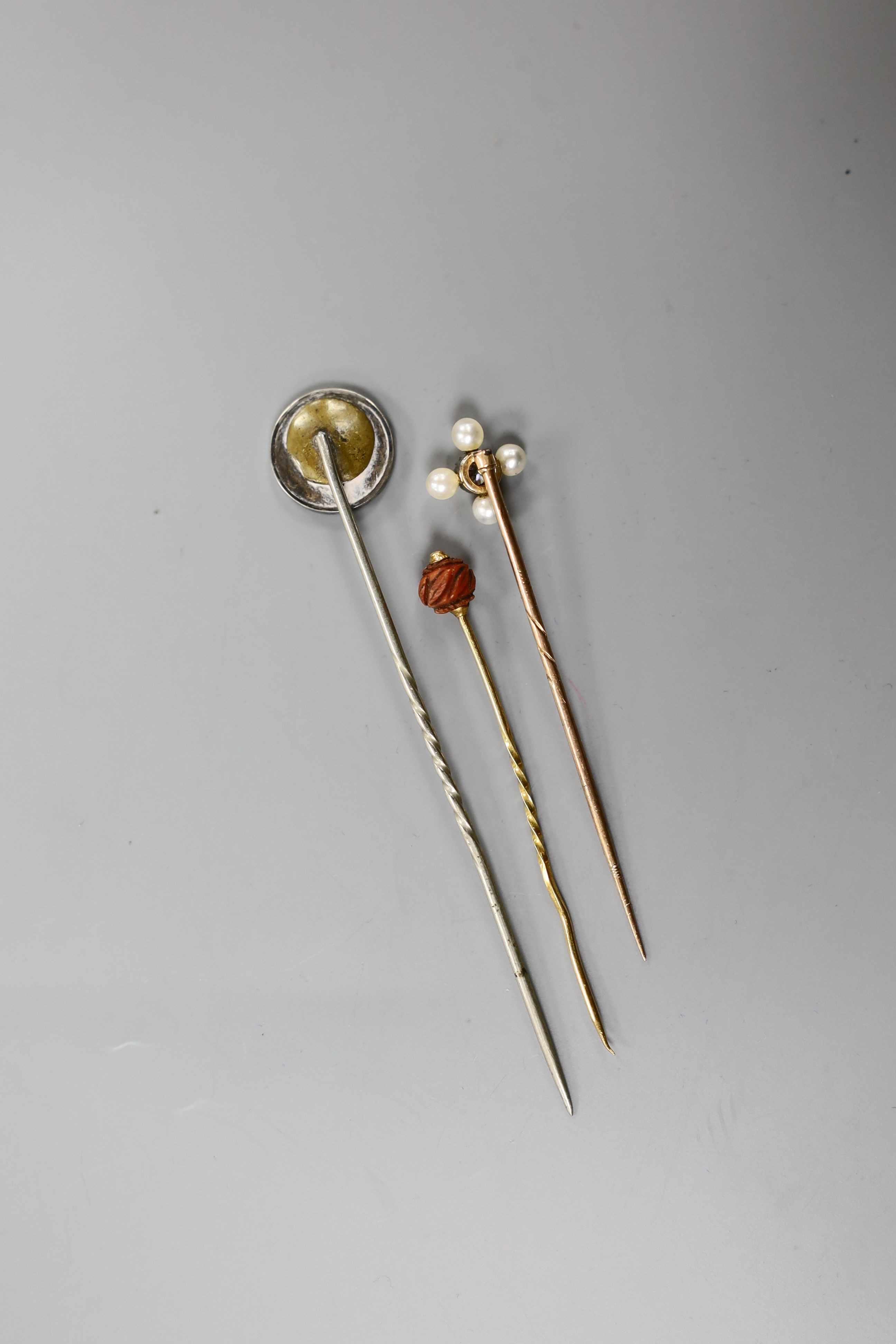 An Edwardian yellow metal, seed pearl and diamond set stick pin, 57mm and two other stick pins.